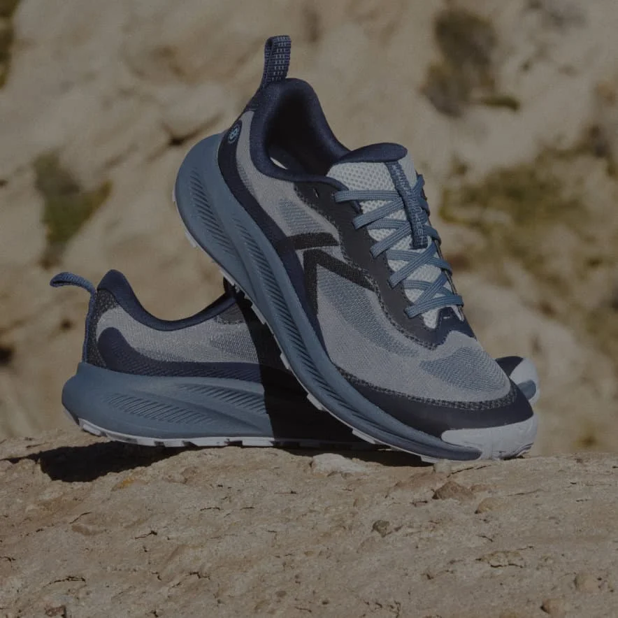 A pair of Navy blue Wander trail running shoes propped up on each other in a desert setting.